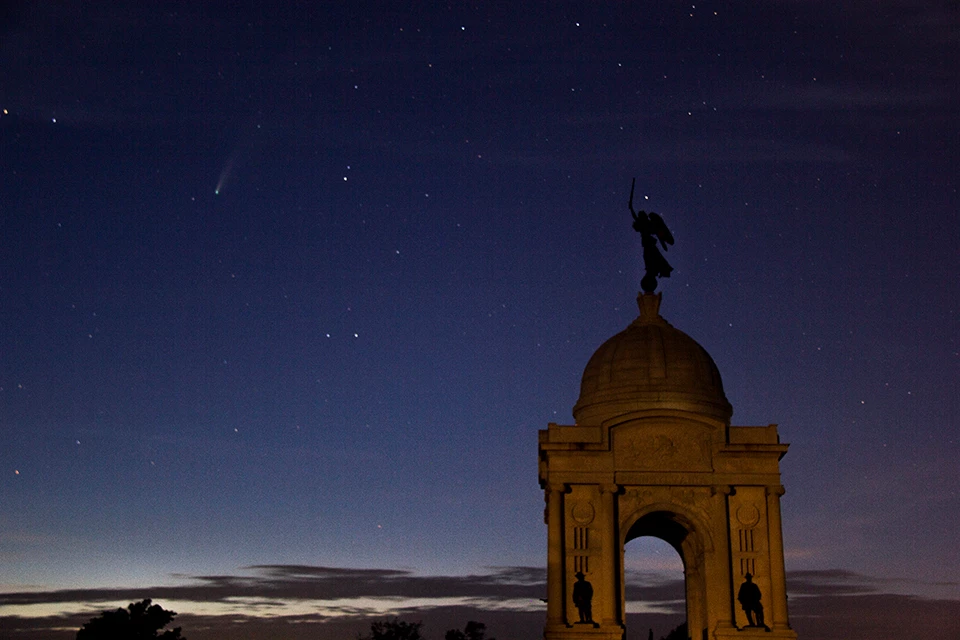The Pennsylvania Memorial with comet Neowise. Photo taken on July 20, 2020. The Pennsylvania Memorial, a large domed monument with a statue at the top, is seen at early evening with a starry sky and a comet in the upper left corner.