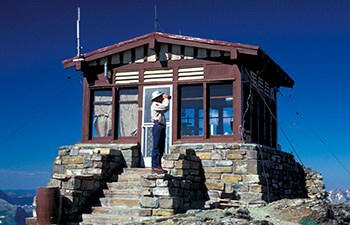 man with binoculars on stone steps of lookout building