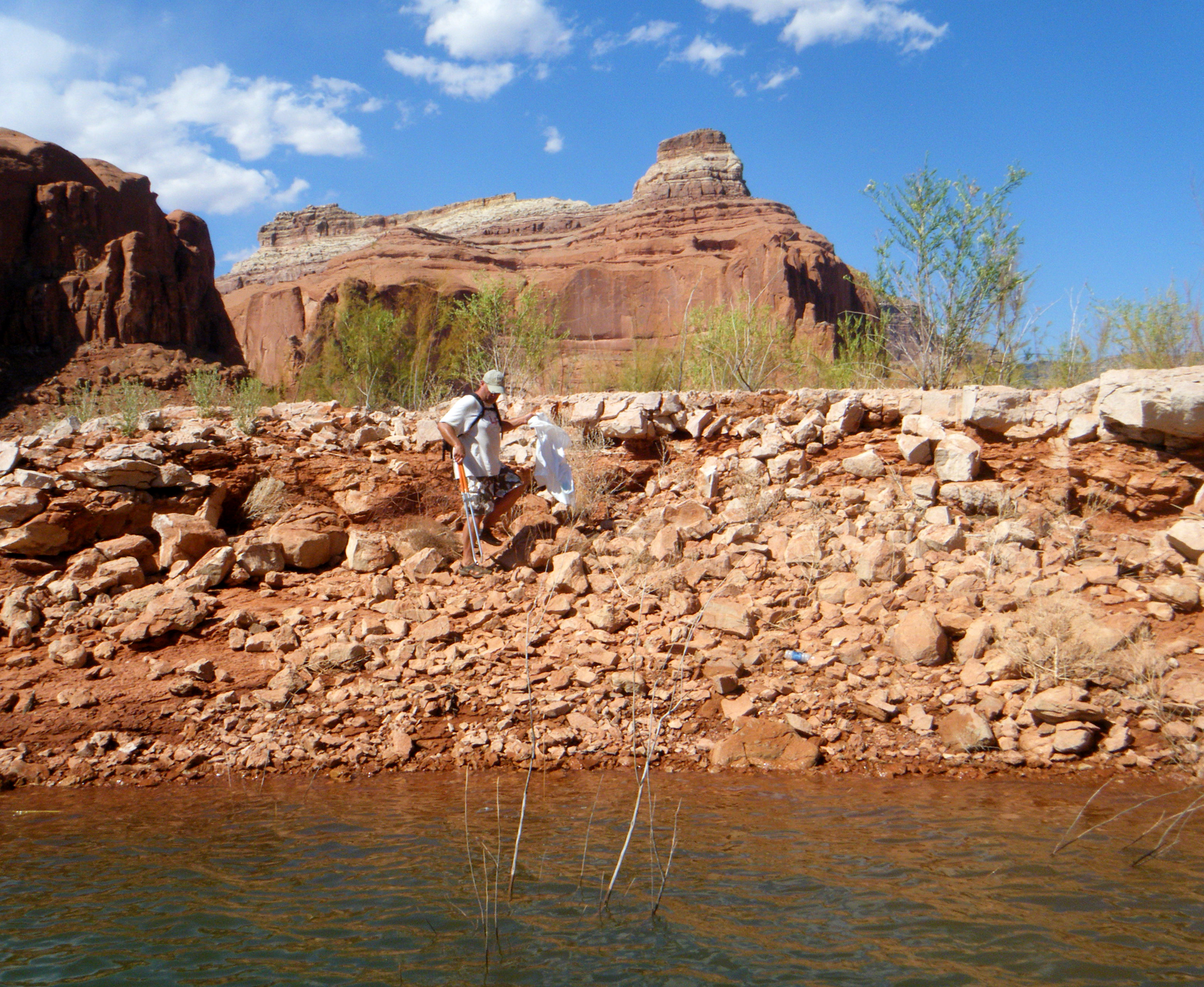 Volunteer uses grabber to pick up litter along rocky shoreline