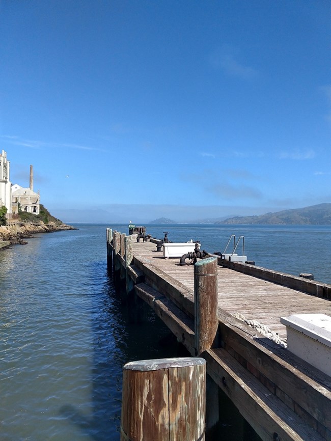 Alcatraz Island finger pier jutting out into bay with historic buildings on left.