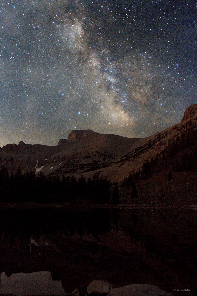 The milky way galaxy rises over Wheeler Peak with Stella Lake in the foreground. A color image taken at night.