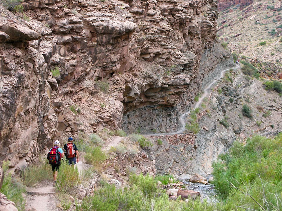 Two hikers descend down the North Kaibab Trail along Bright Angel Creek