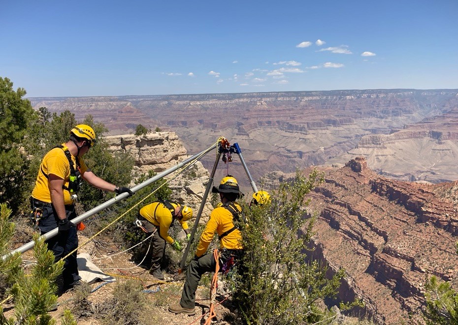 A team of rescuers manages a technical rescue system at the edge of canyon