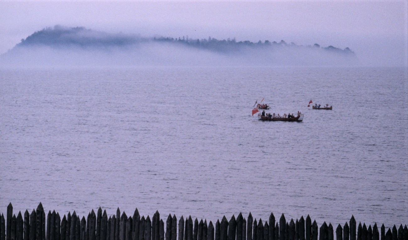 Voyageurs paddling before Grand Portage Island (reenactment).