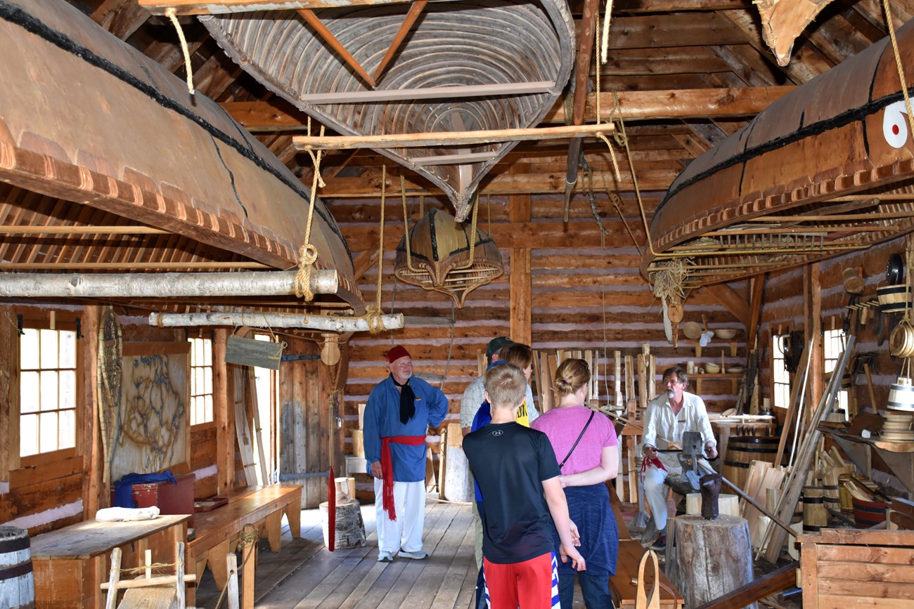 People inside a historic wood building with canoes.