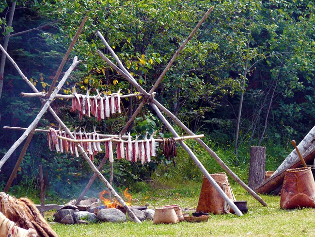 Fish hanging on a traditional wooden pole rack over a fire.