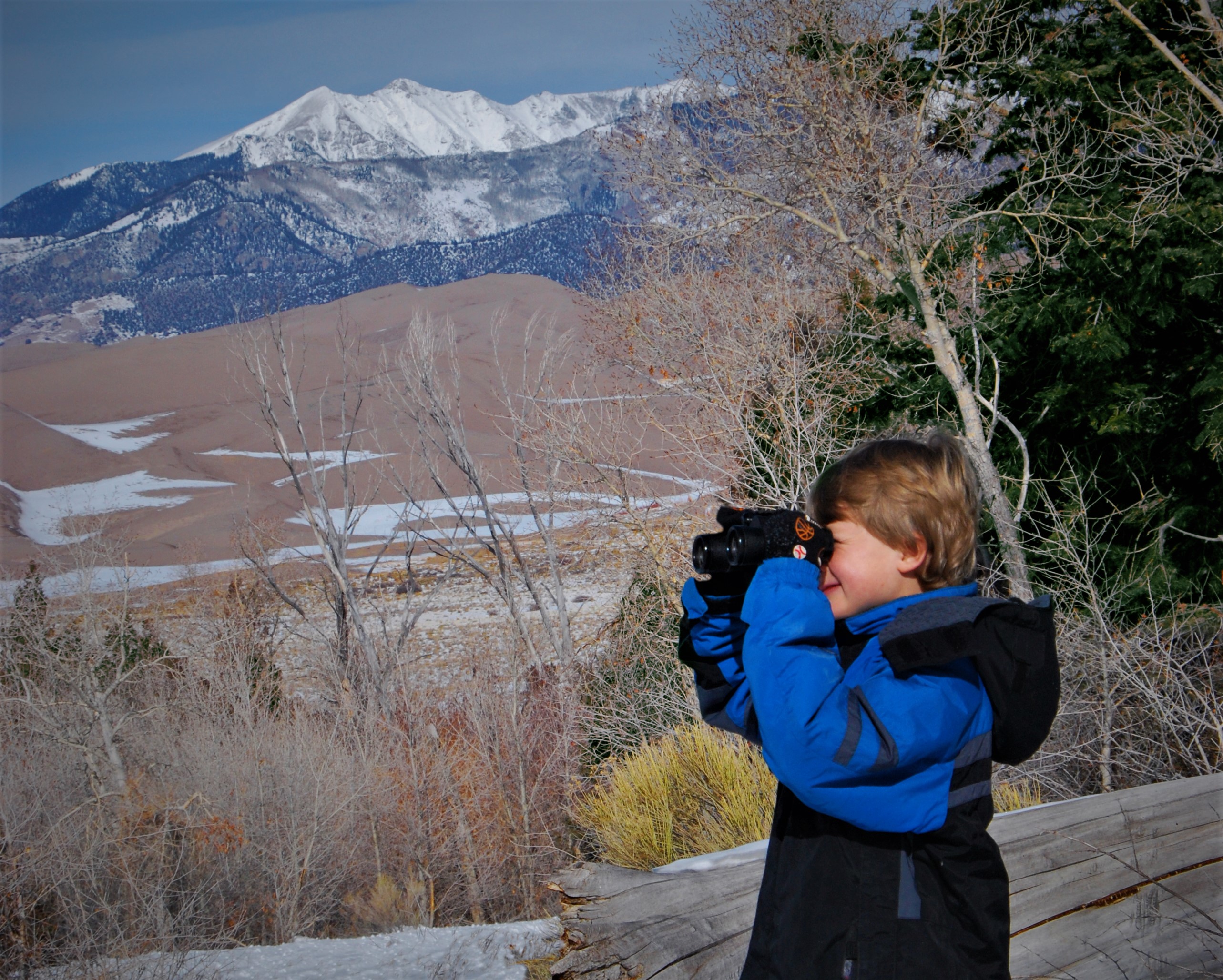 Boy in a winter coat counts birds in the snow at Great Sand Dunes NPP in 2012.