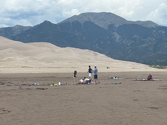 A dry creekbed with children digging, dunes and mountain in background