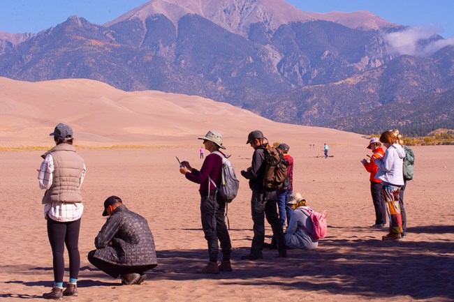 An artist leads adults in sketching in front of the dunes and mountains