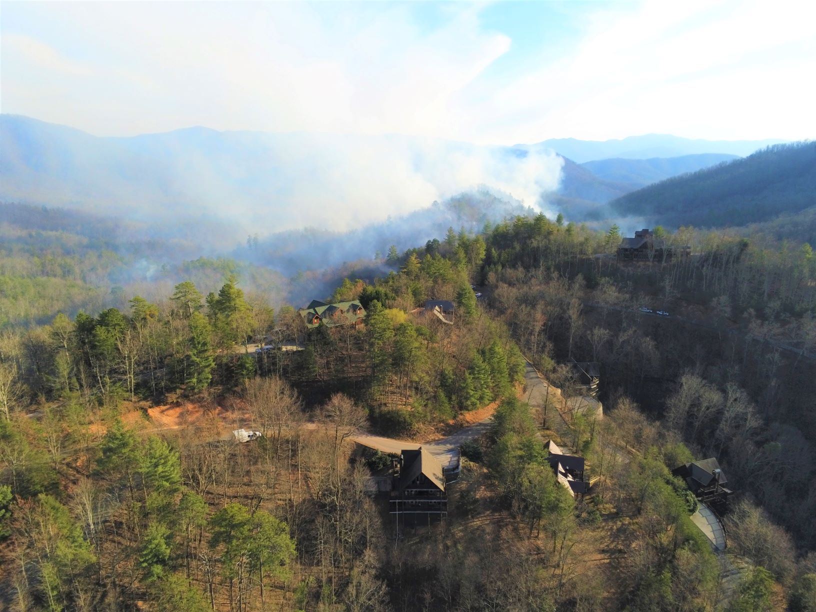 Smoke from prescribed burn above mountains near houses.