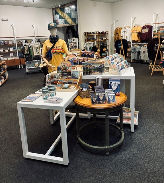 Multiple tables and other fixtures with a variety of shirts, pictures, and plush animals displayed.