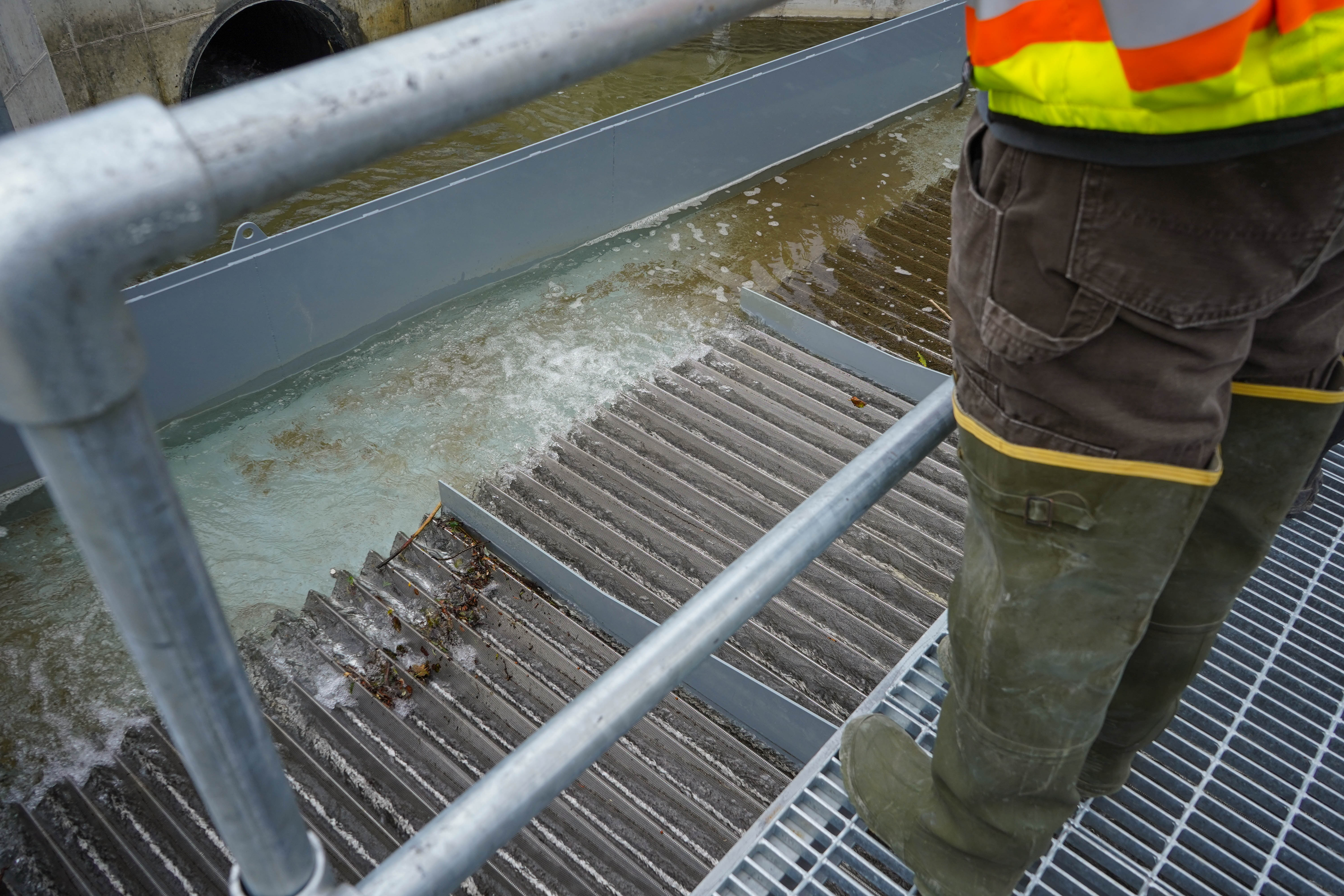 boots on a metal walk above a screen water is flowing over