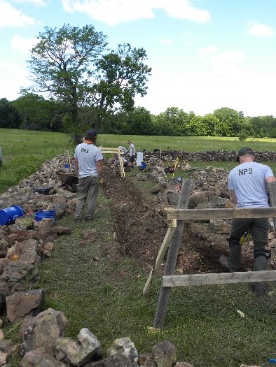 Skilled Masons wearing NPS shirts are repairing a cemetery wall at George Washington Carver National Monument.