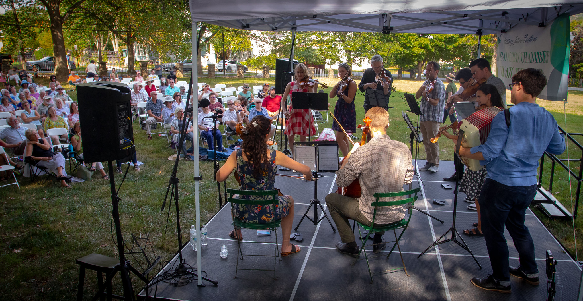 Ten musicians play stinged instruments on a stage in front of a crowd.