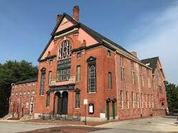 An image of a red brick building, on the corner of two streets. The building is called the Orchard Street Church (Methodist Episcopal)