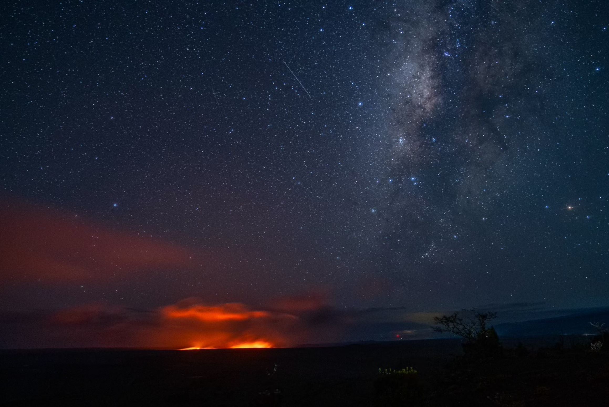 Milky Way and glow from an eruption seen from a distance at night.