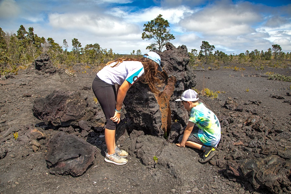 A young boy and his mother peer into a lava tree mold