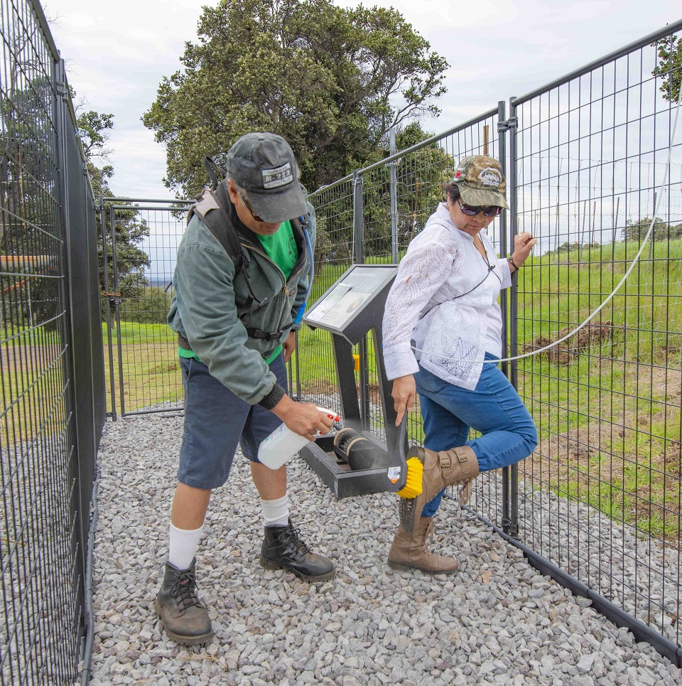 Two hikers clean their boots at the new Rapid ʻŌhiʻa Death decontamination station in Kahuku