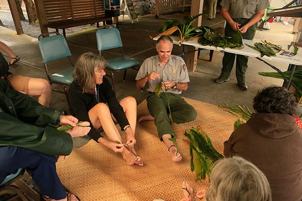 Ranger Dean demonstrates how to make a tī leaf lei at the Kīlauea Visitor Center lānai