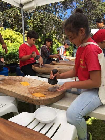 A young girl pounds poi at Hawaii Volcanoes National Park