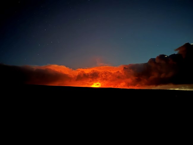 Bright red glow along horizon surrounded by darkness