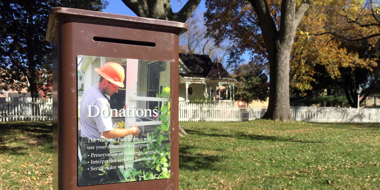 An illustrated sign identifies a metal box as a donation box.