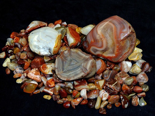 Assorted small stones are polished to reveal swirls of reds, browns, and white.
