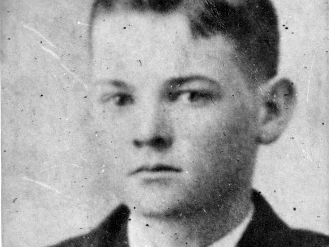 A black and white portrait photo of a fourteen year old boy in a suit.