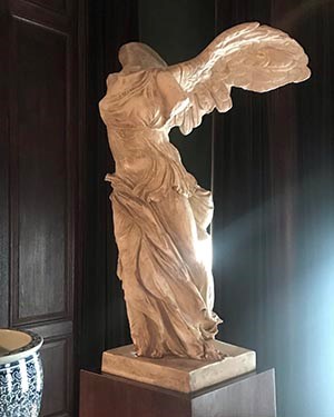A plaster statue of a headless winged figure wearing a flowing robe.