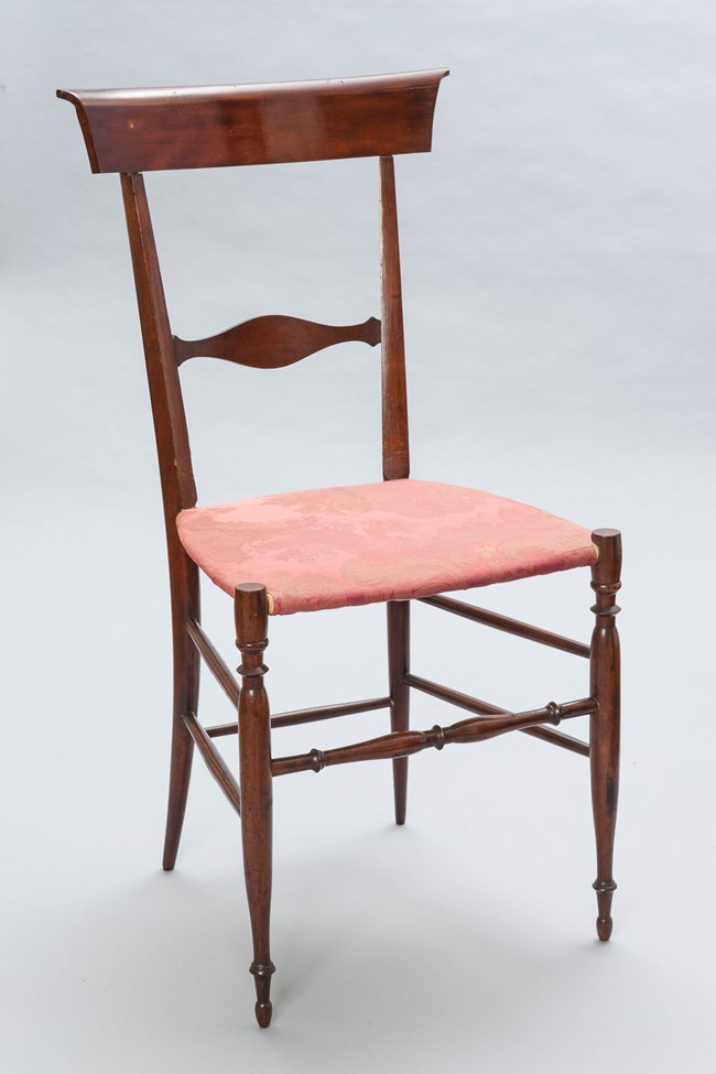 A delicate wood side chair with damask upholstered seat.