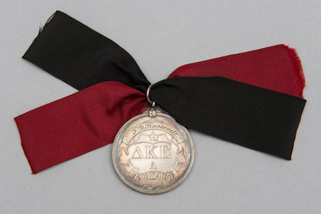 A silver medal with red and black silk ribbon