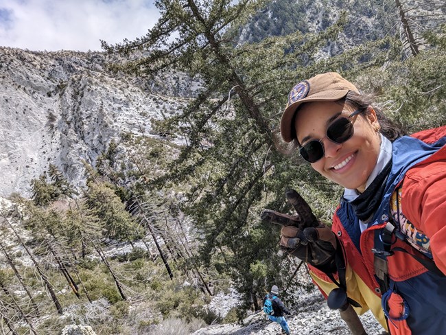 Wendy Zamora, MOJN Physical Science Technician Smiling woman in a rocky, open-forested, mountain landscape.
