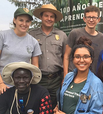 Man in NPS uniform stands with diverse group of young people