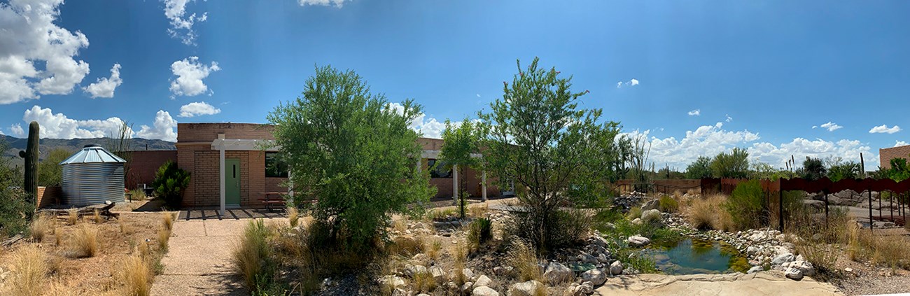 Silver water tank, building, trees, and water feature