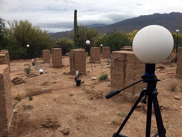 White globes sit on tripods among adobe walls in rows