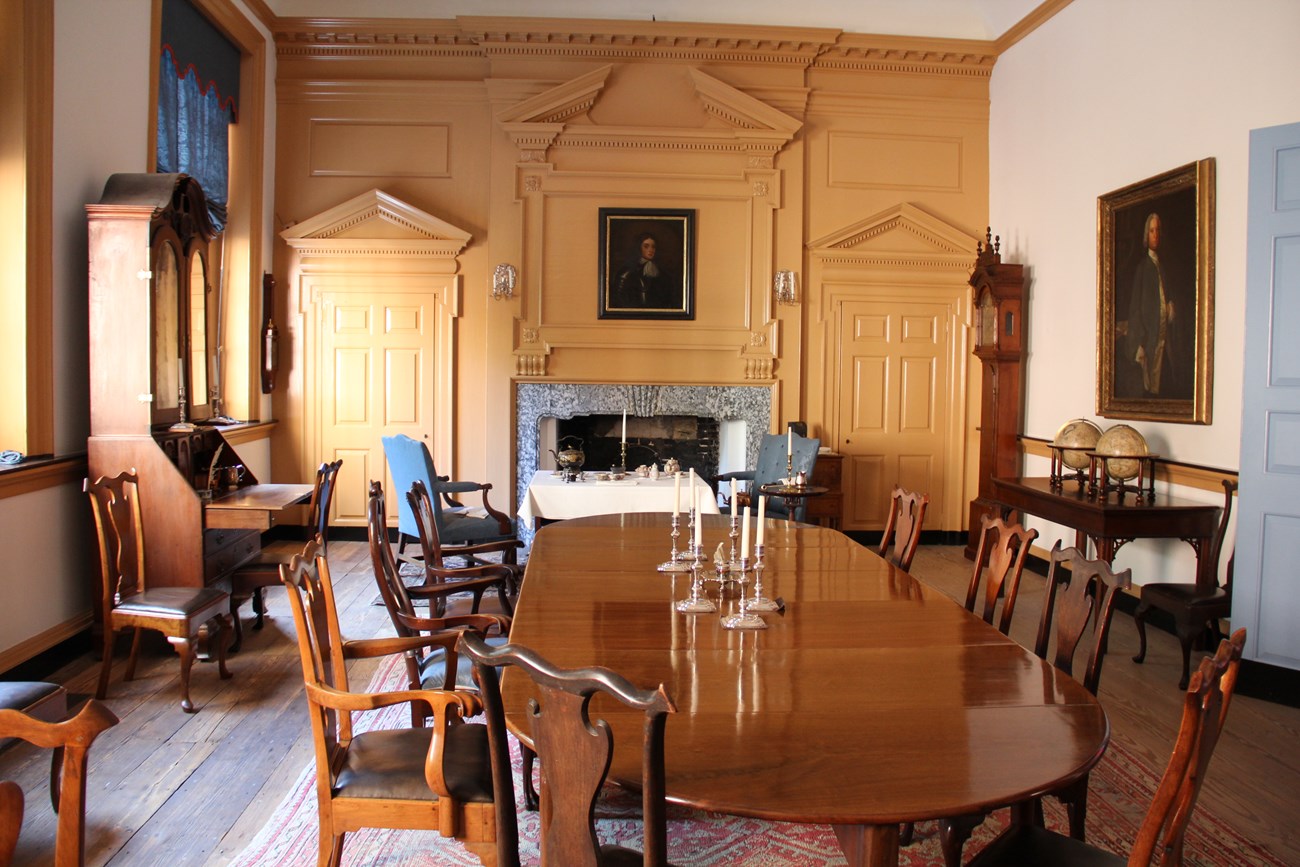 View of governor's council chamber with large elegant wood table, surrounded by eight wood chairs.