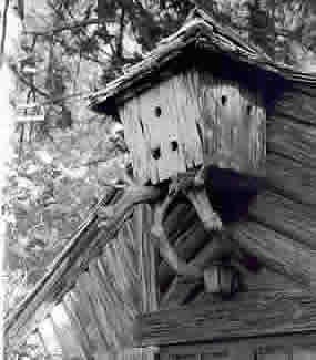photo of bird house attached to top front of cabin designed to match the log cabin