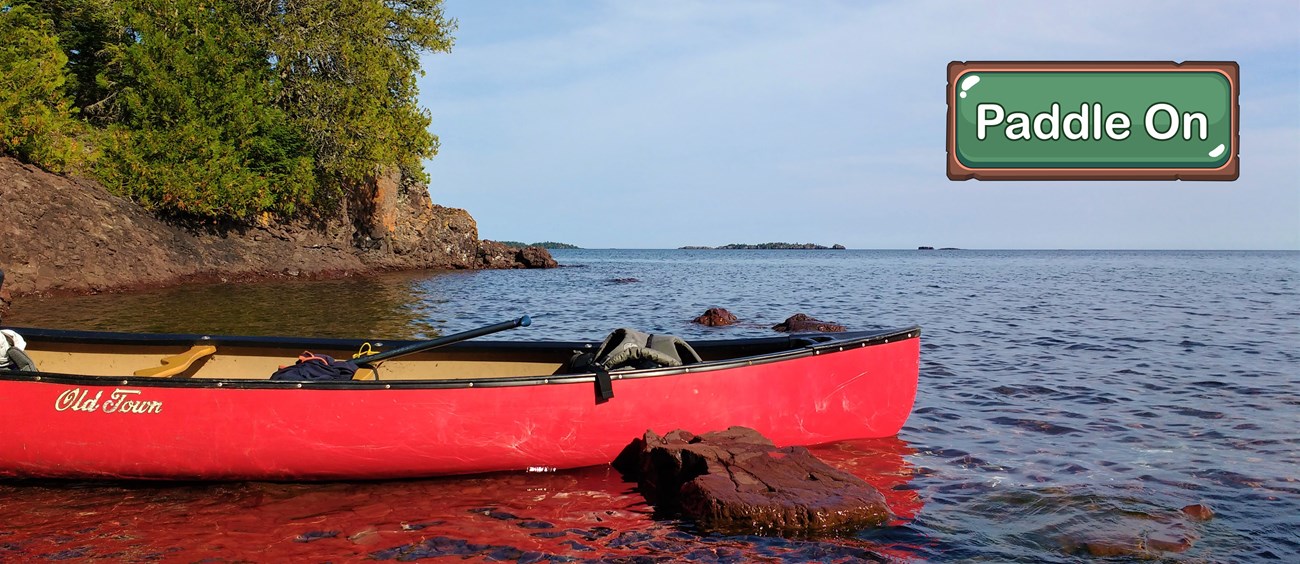 A red canoe rests in shallow water.
