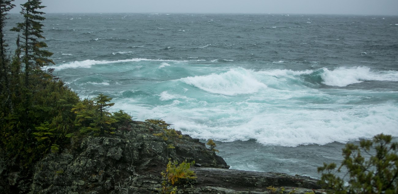 Large waves rolling into a rocky shoreline.