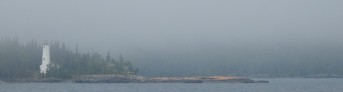 A tall white lighthouse in fog.