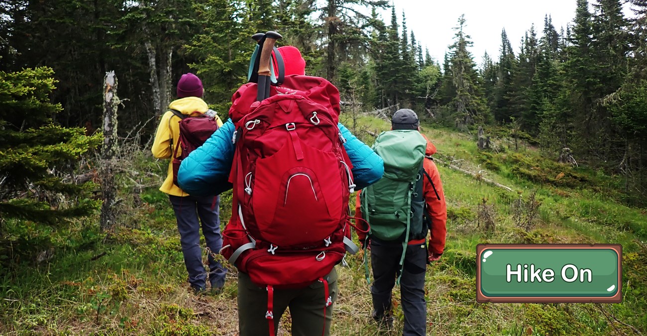 Three hikers with large backpacks on a grassy ridge.