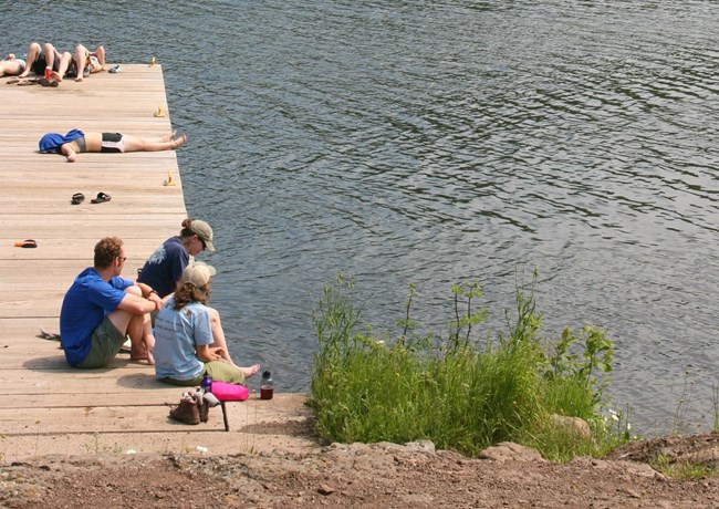 People sit on a large wooden dock.