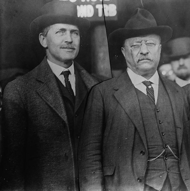 two men in suits standing side by side