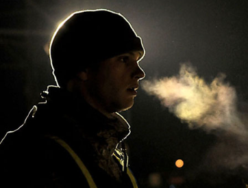 A man wearing a ski hat is seen, with a cloud forming his breath.