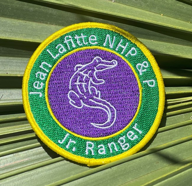 A patch in Mardi Gras colors of an alligator with the text "Jean Lafitte NHP&P Jr Ranger."