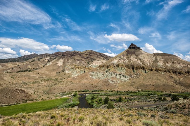 Hills with rocky outcrops on the top and in the middle. A river winds through a valley below.