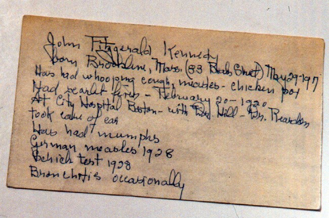 Handwritten, cursive notes in dark ink on a beige paper note card.