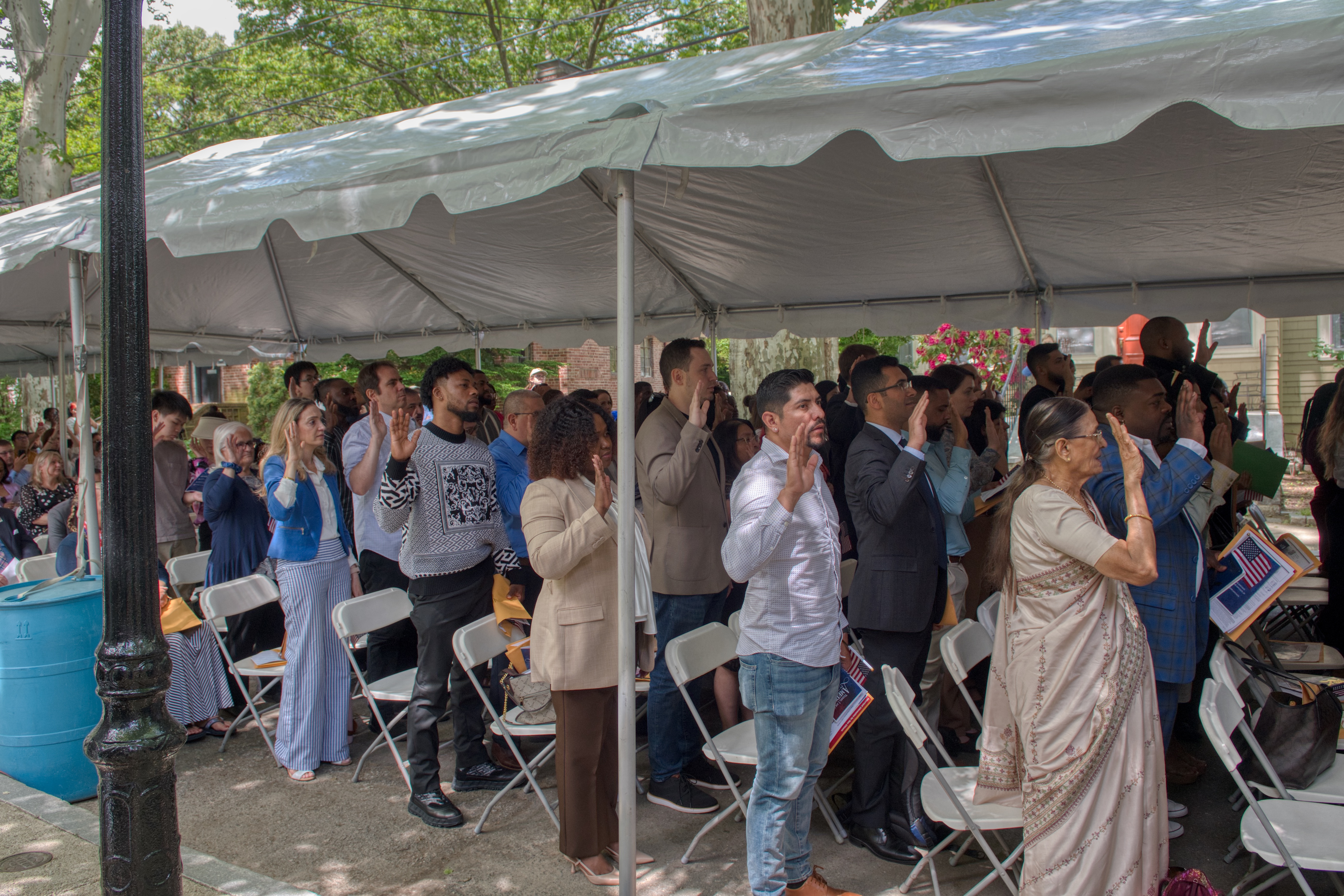 A group of people standing with their hands raised under a white tent