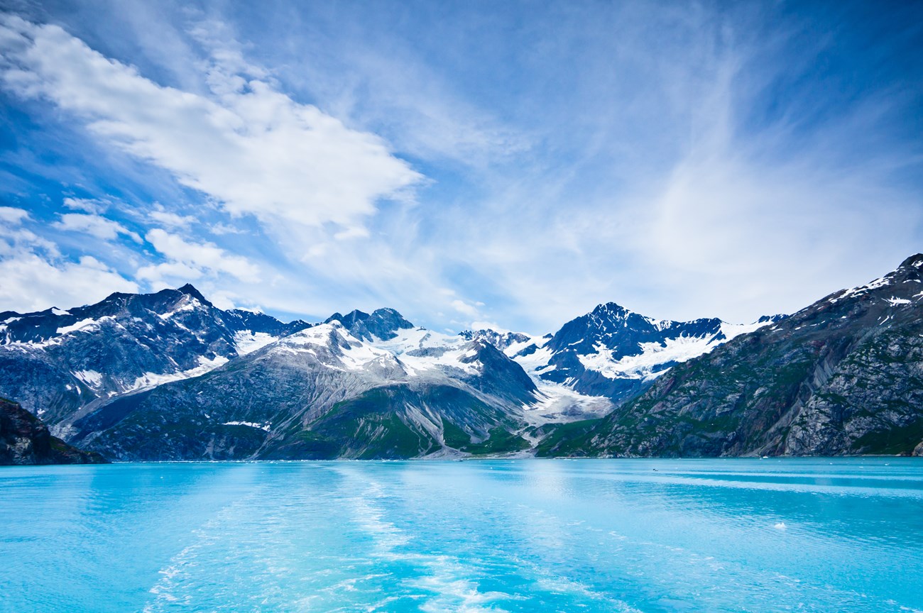 Icy waters leading up to a large glacier and mountains.
