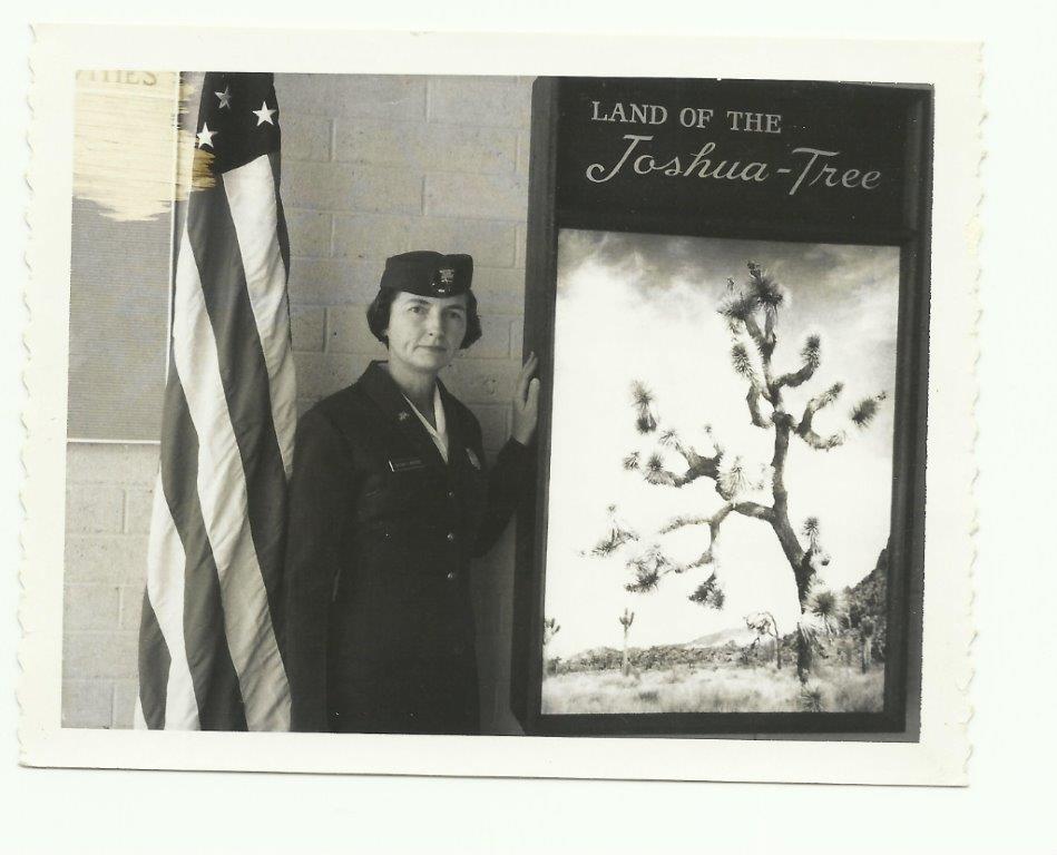 black and white photo of a female park ranger standing next to a sign that reads "Land of the Joshua-Tree"